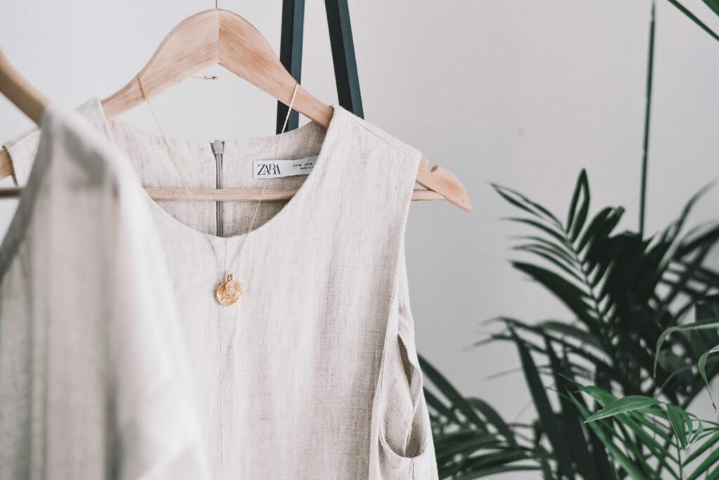 Stylish beige dress hanging indoors, showcasing minimalist fashion amidst green plants.